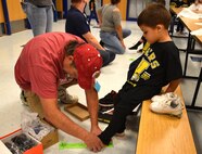 John Ide measures the foot of a Wheeler Elementary student Oct. 6. Ide, a program manager with the 38th Cyberspace Engineering Group’s Requirements Implementation Section, was one of the volunteers on hand at the elementary school to help distribute new shoes and socks to the 400 students.