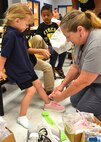 Vicki Morrison, a 38th Cyberspace Engineering Group Requirements Implementation Section program manager, checks the fit on a new pair of pink shoes for a Wheeler Elementary School student.