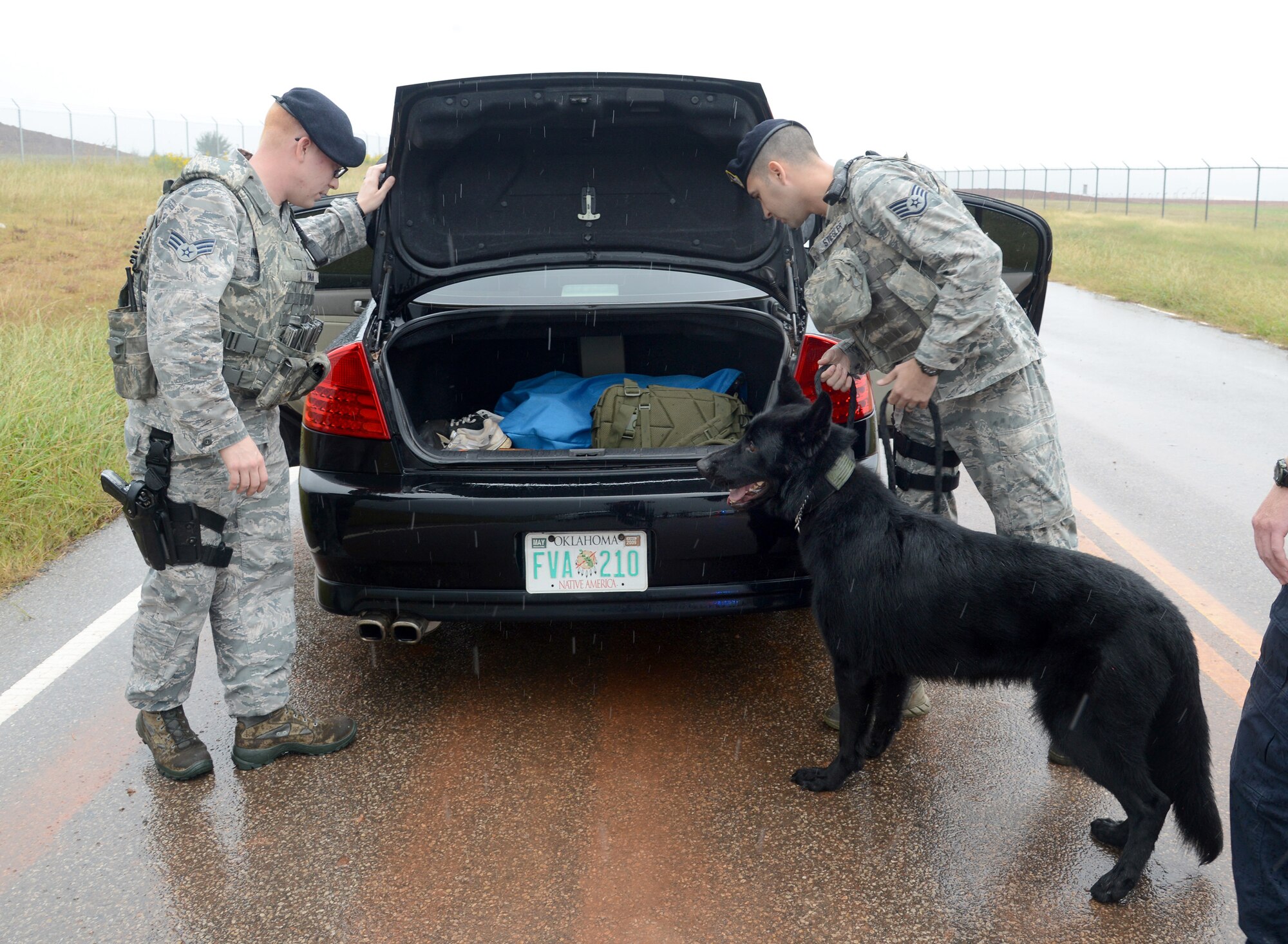 Senior Airman Chris Inman, left, and Staff Sgt. James Stiegler, both with the 72nd Security Forces Squadron, and Military Working Dog Kali inspect the contents of a vehicle which was used in a gate-runner scenario for a War Wagon exercise Oct. 4.