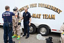 Lt. Chad Beals, left, and Capt. David Jones, right, help Lt. Jeff Briley, all with the Tinker Fire and Emergency Services, with his gas mask and Level B Hazmat suit. The suit helps keep liquids or chemicals off of the skin while working in the decontamination area of the chemical, biological, radiological, nuclear, explosive exercise Oct. 5.