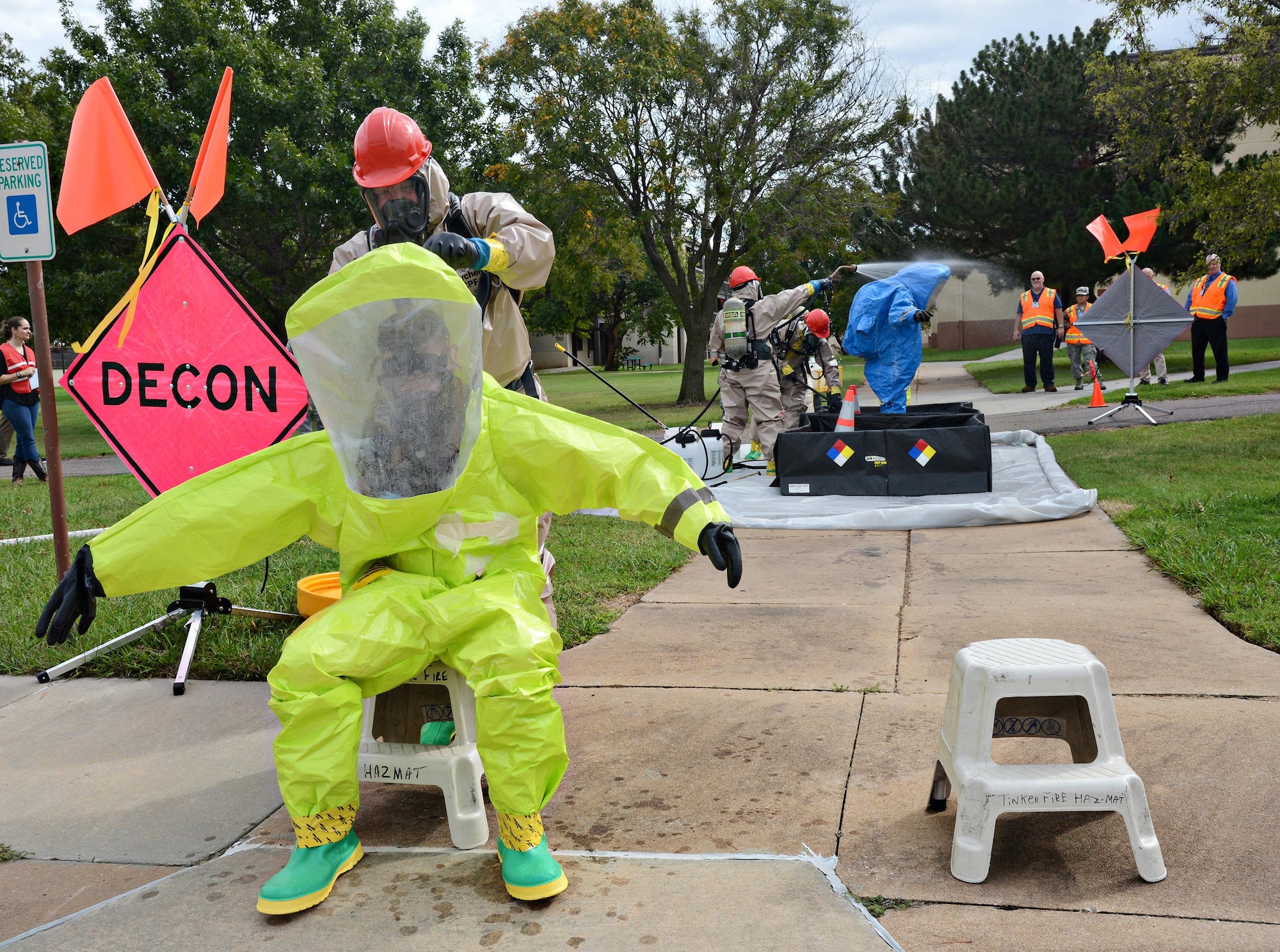 In the foreground, Lt. Matthew Hau, with the Tinker Fire and Emergency Services, helps Staff Sgt. Wesley Smith, with the 72nd Aerospace Medicine Squadron’s Bioenvironmental Flight, out of his Level A Hazmat suit. In the background, Lt. Jeff Briley and Lt. Kyle Abernathy spray simulated chemical residue off of Corey Morgan, with 72nd ABW Civil Engineering Direcorate Emergency Management, in the Hazmat decontamination area of the CBRNE exercise Oct. 5. Air Force Materiel Command, Air Force Sustainment Center and 72nd Air Base Wing Inspector General’s Office inspectors monitored this exercise, along with the pre-deployment mobility line and gate runner exercises Oct. 4.