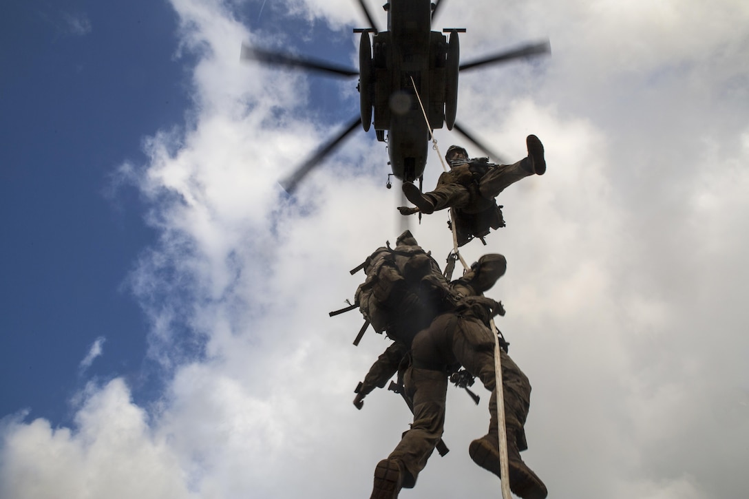 Troops dangle off a rope from a helicopter during an extraction exercise.