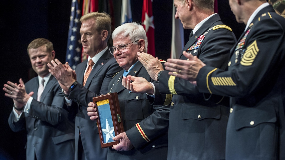 The deputy defense secretary claps during a ceremony for a Medal of Honor recipient.