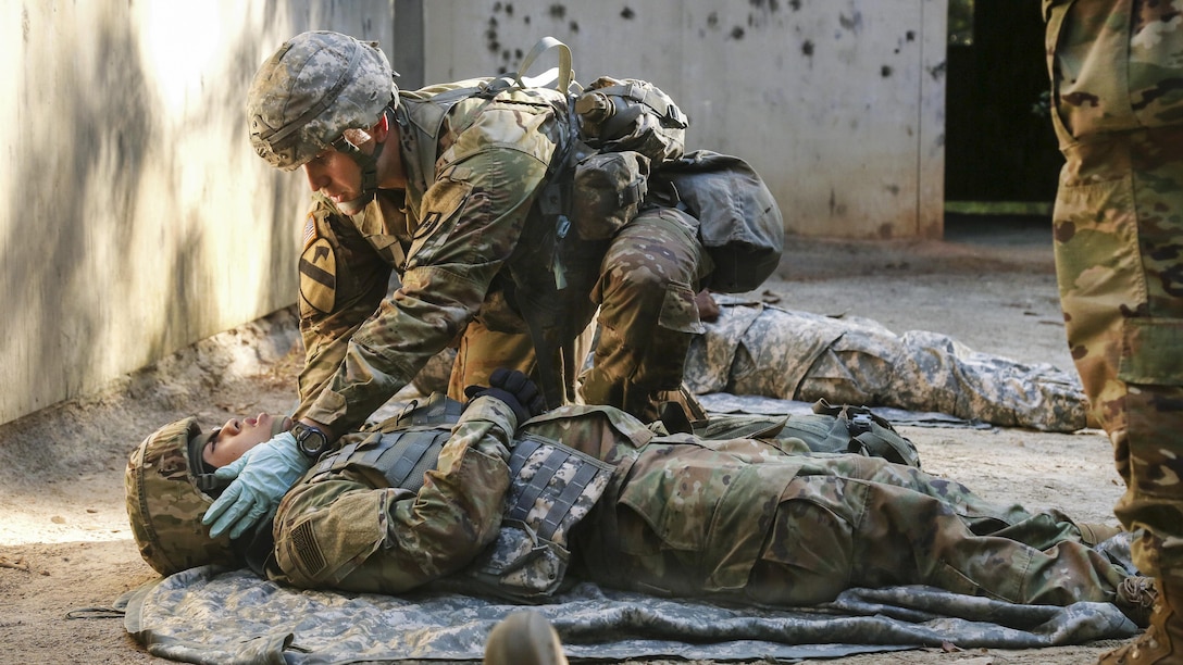 A soldier checks a simulated injured soldier to perform tactical field medical care