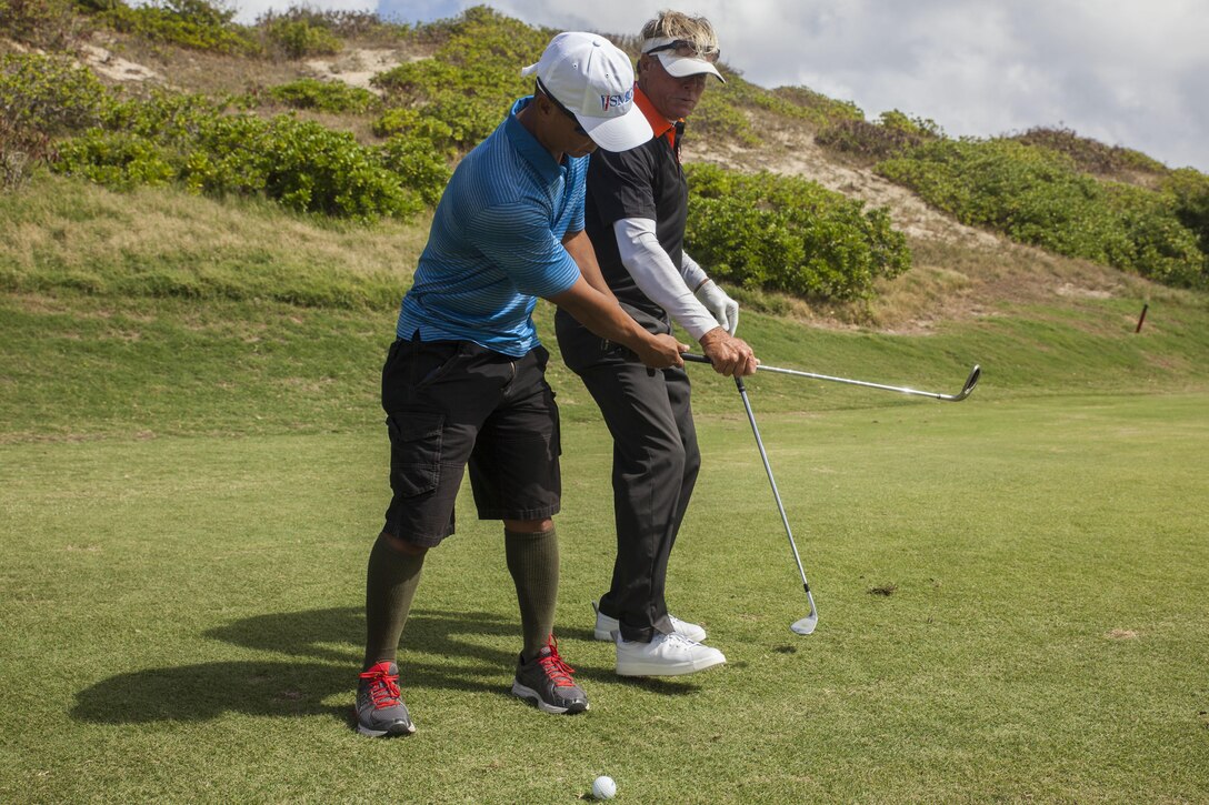 Leland Lindsay, a director of instruction with the Golf Academy of the Pacific, assists a student with proper golf swing techniques during the Warriors Golf Clinic, hosted by the Salute Military Golf Association (SMGA), at the Kaneohe Klipper’s Golf Course, Marine Corps Base Hawaii, Oct. 21, 2017. The SMGA is a non-profit organization that serves Post 9/11 wounded veterans by introducing the sport of golf as a diversion for rehabilitation through Warrior Golf Clinics. (U.S. Marine Corps photo by Cpl. Jesus Sepulveda Torres)
