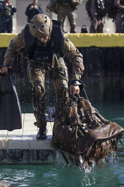 A student with the Reconnaissance Team Leader Course (RTLC) exits the water with his gear at the base Waterfront Operations pier prior to conducting a helocast exercise, Marine Corps Base Hawaii, Oct. 19, 2017. RTLC is an 8-week advanced joint-service course that takes place in three key geographical regions of operation such as classes at Camp Pendleton, California, desert patrol operations in Yuma, Arizona, and ending with jungle and amphibious exercises across Oahu, Hawaii. (U.S. Marine Corps photo by Cpl. Jesus Sepulveda Torres)