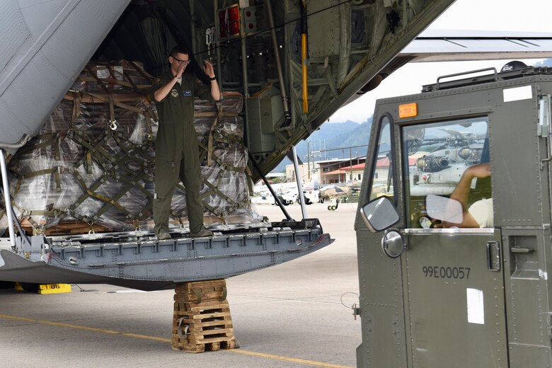 Senior Airman David Heinz, a loadmaster from the 40th Airlift Squadron, directs an air transporter from the 612th Air Base Squadron, driving a K-loader toward the C-130J.  Heinz worked with the air transporters to offload the pallets during a routine global channel mission Oct. 18, 2017 to Soto Cano Air Base, Honduras, delivering sustainment and supplies to Airmen supporting Joint Task Force Bravo.  The Airmen from the 317th Airlift Wing at Dyess Air Force, Texas, routinely support the Honduras mission, a tasking from the 618th Air Operations Center.  (Air Force photo by Master Sgt. Kristine Dreyer)