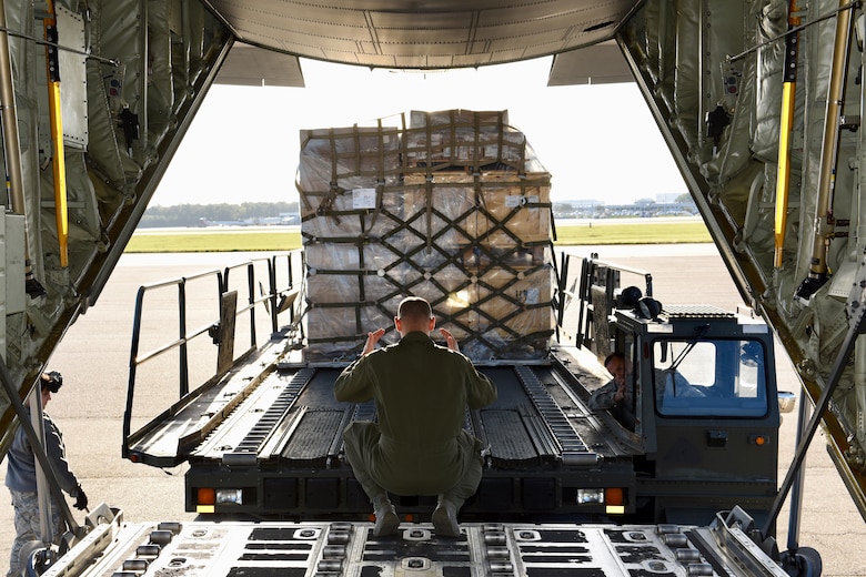 Senior Airman David Heinz, a loadmaster from the 40th Airlift Squadron, directs an air transporter at Charleston Air Force Base, S.C., while loading pallets destined for Soto Cano Air Base, Honduras, Oct. 18, 2017.  A C-130J crew from the 317th Airlift Wing at Dyess Air Base, Texas, completed a routine global channel mission delivering sustainment and supplies to Airmen supporting Joint Task Force-Bravo. Airmen from Soto Cano rely on the mission to bring items needed to complete their mission while stationed in Central America.