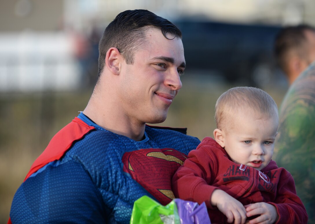Staff Sgt. Tyler Perry, a security forces evaluator assigned to the 28th Security Forces Squadron, holds a child for a picture at Ellsworth Air Force Base, S.D., Oct. 11, 2017. Local police and 28th SFS members posed for pictures, handed out candy and raised awareness about Crime Prevention Month during a superhero parade. (U.S. Air Force photo by Airman 1st Class Thomas Karol)