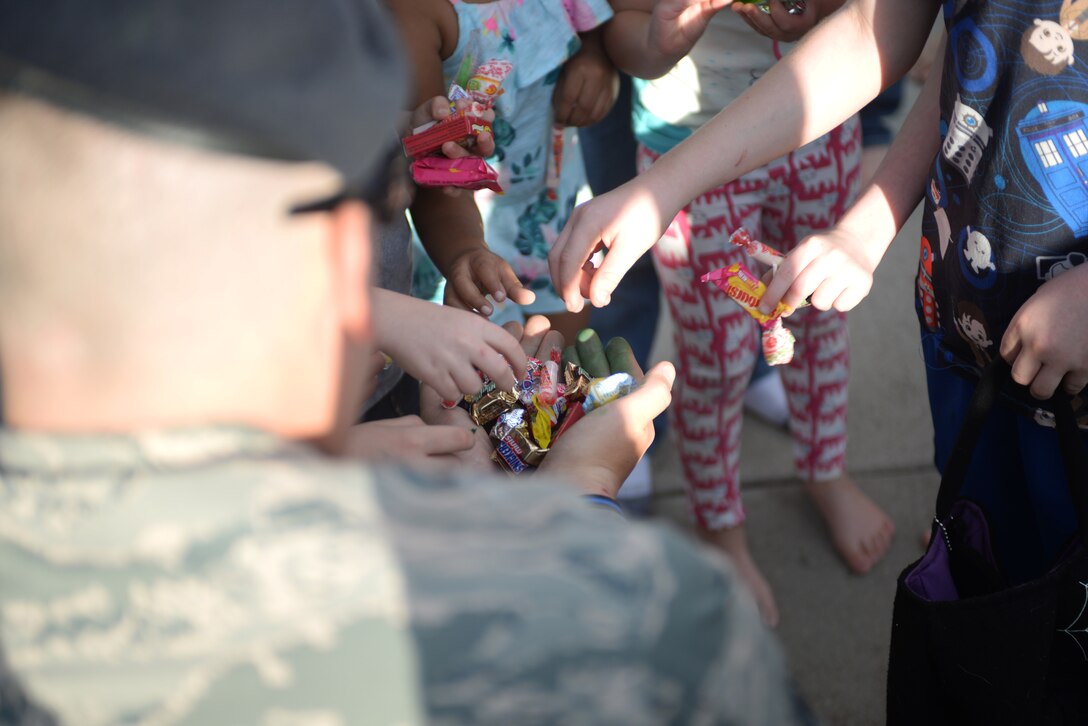 Tech. Sgt. Nathan Patterson, the police services non-commissioned officer in charge assigned to the 28th Security Forces Squadron, gives out candy to children during an event for Crime Prevention Month at Ellsworth Air Force Base, S.D., Oct. 11, 2017. Patterson and other law enforcement members build relationships and strengthen their team in order to be more effective in preventing crime by holding events such as the Superhero Parade. (U.S. Air Force photo by Airman 1st Class Thomas Karol)