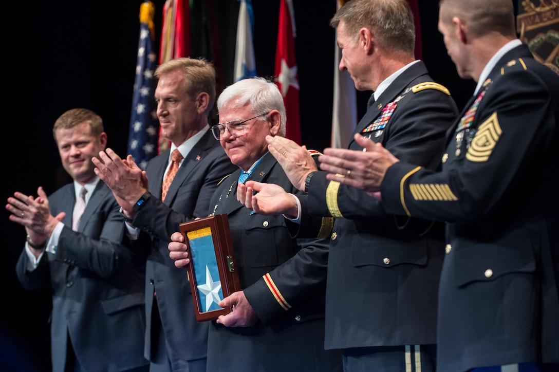 Leaders stand with a Medal of Honor recipient at a ceremony.