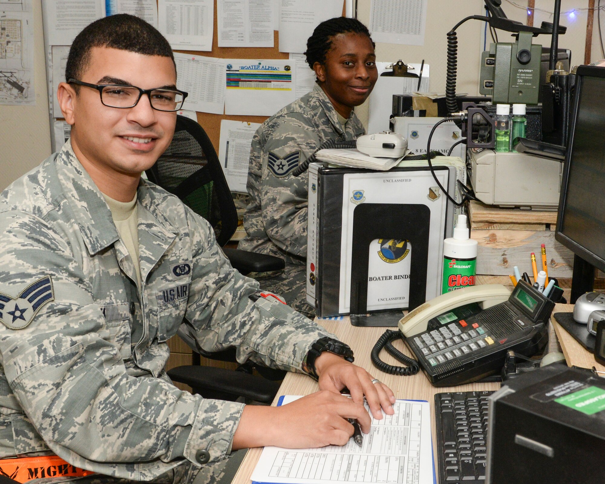 U.S. Air Force Senior Airman Johan Pena, foreground, junior controller and Staff Sgt. Takneisha Boatright, senior controller, both assigned to the 8th Expeditionary Air Mobility Squadron/Air Mobility Command Center, sit at their computers in the AMCC at Al Udeid, Air Base, Qatar, Aug. 22, 2017.