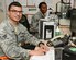 U.S. Air Force Senior Airman Johan Pena, foreground, junior controller and Staff Sgt. Takneisha Boatright, senior controller, both assigned to the 8th Expeditionary Air Mobility Squadron/Air Mobility Command Center, sit at their computers in the AMCC at Al Udeid, Air Base, Qatar, Aug. 22, 2017.