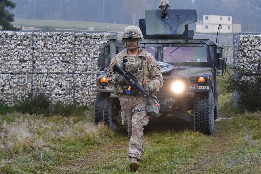 A soldier walks ahead of a humvee.