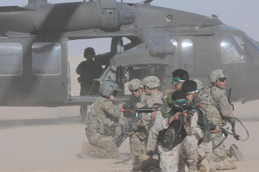 Soldiers in position outside of a helicopter.