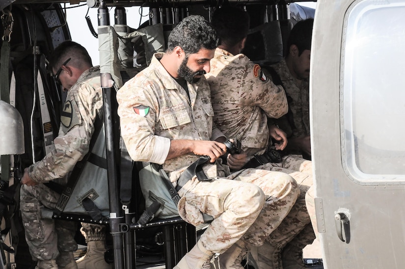 Three soldiers sitting in a helicopter.