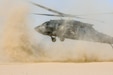 Helicopter takes off, stirring up a cloud of dust.