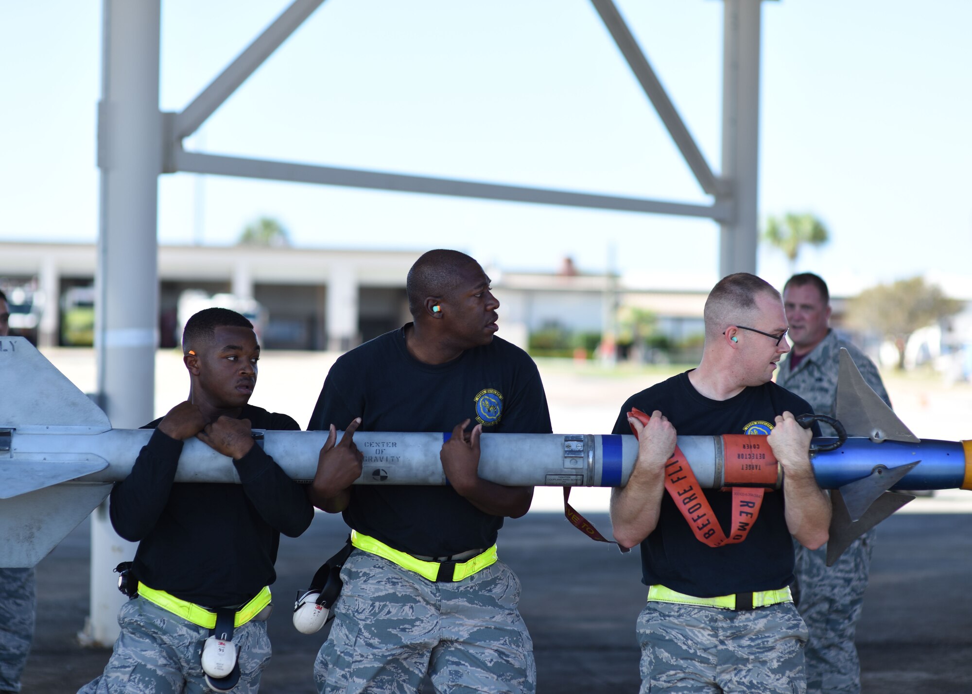 Airmen from the 325th Aircraft Maintenance Squadron, carry a training missile to be loaded onto an F-22 Raptor