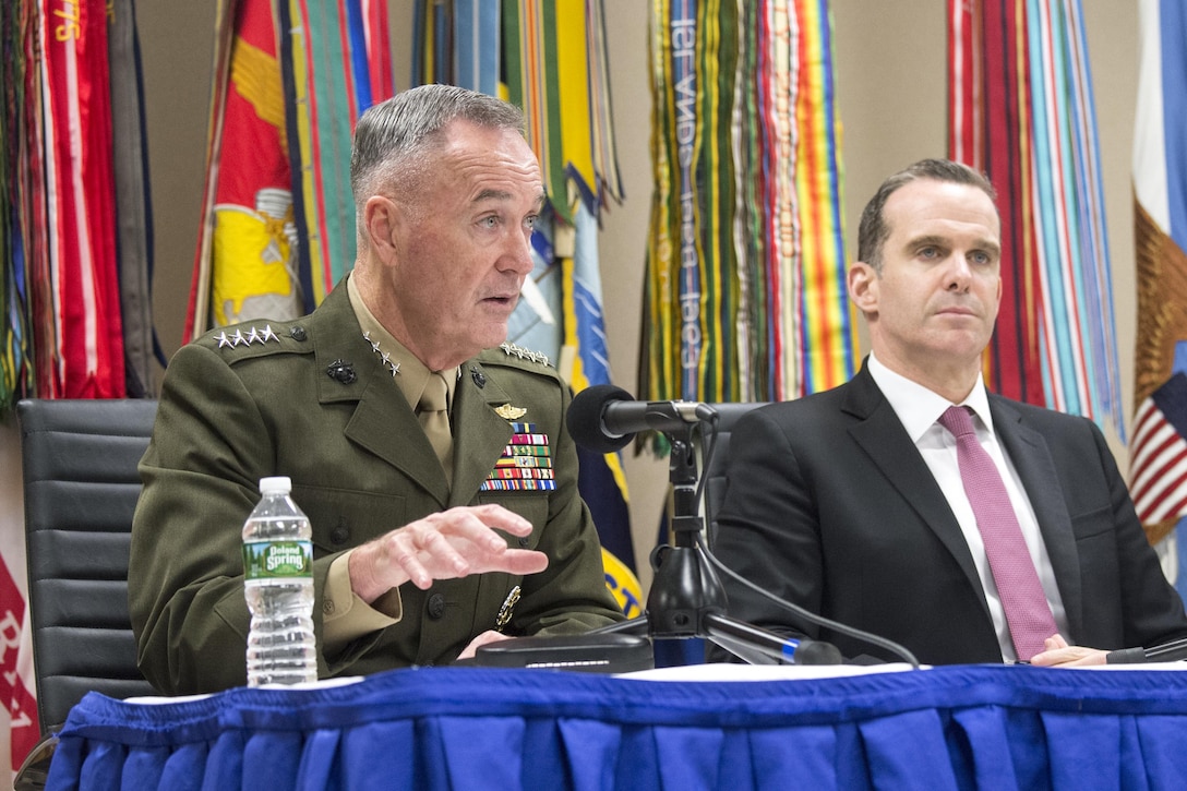 Marine Corps Gen. Joe Dunford speaks at a news conference while seated alongside Brett H. McGurk.