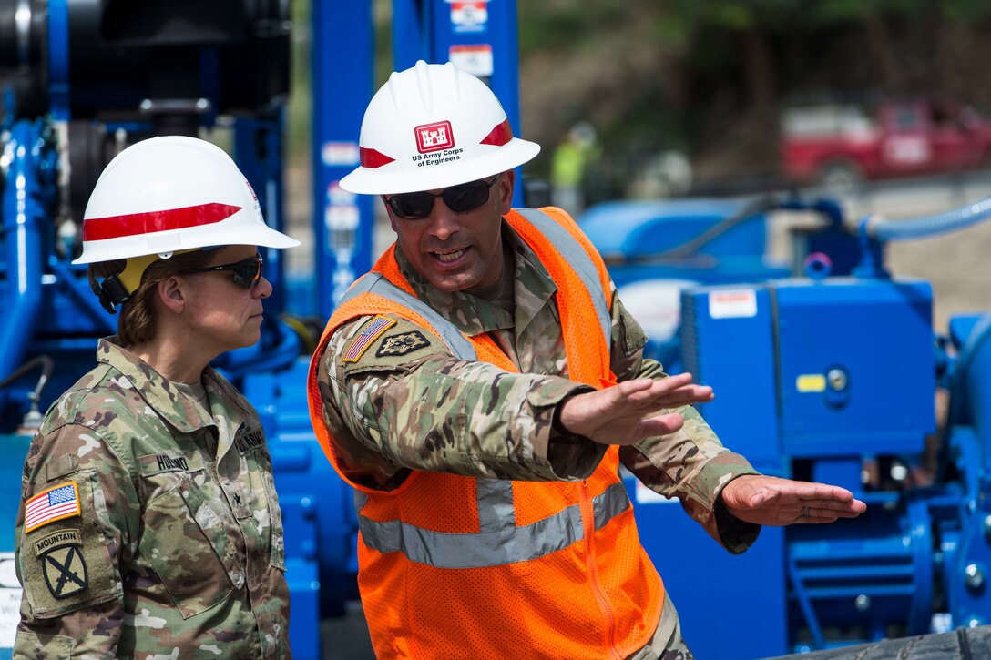 An Army general talks with a soldier wearing protective equipment.