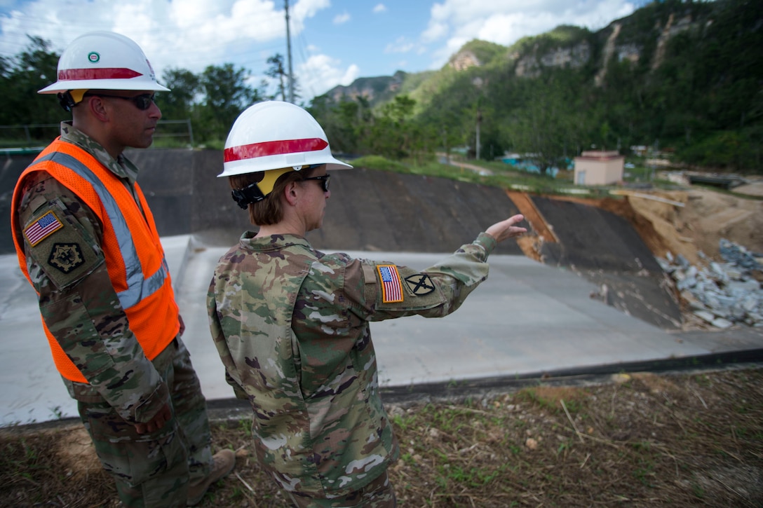 Soldiers wearing construction helmets view work at a dam in Puerto Rico.