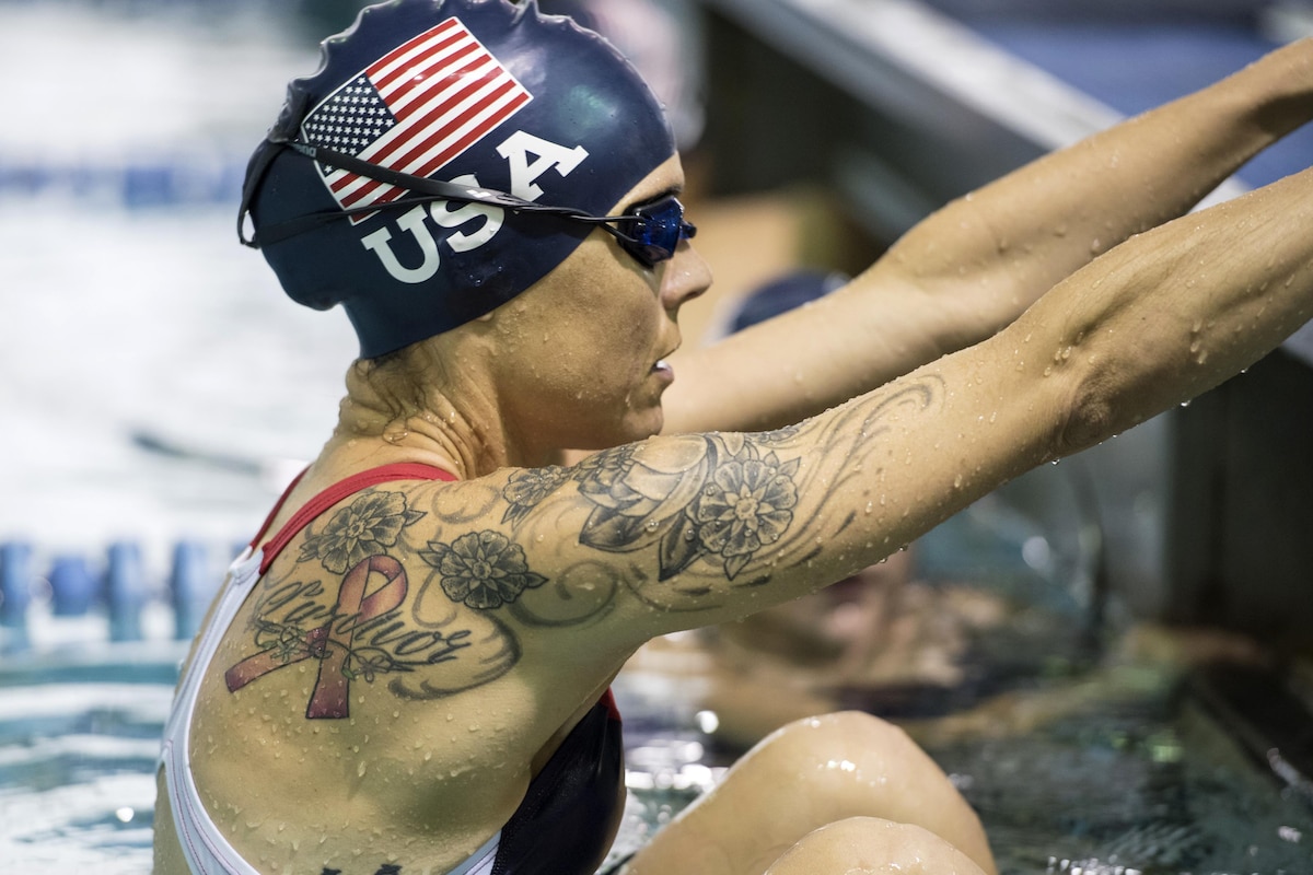 A swimmer is in the water holding the side of the pool.