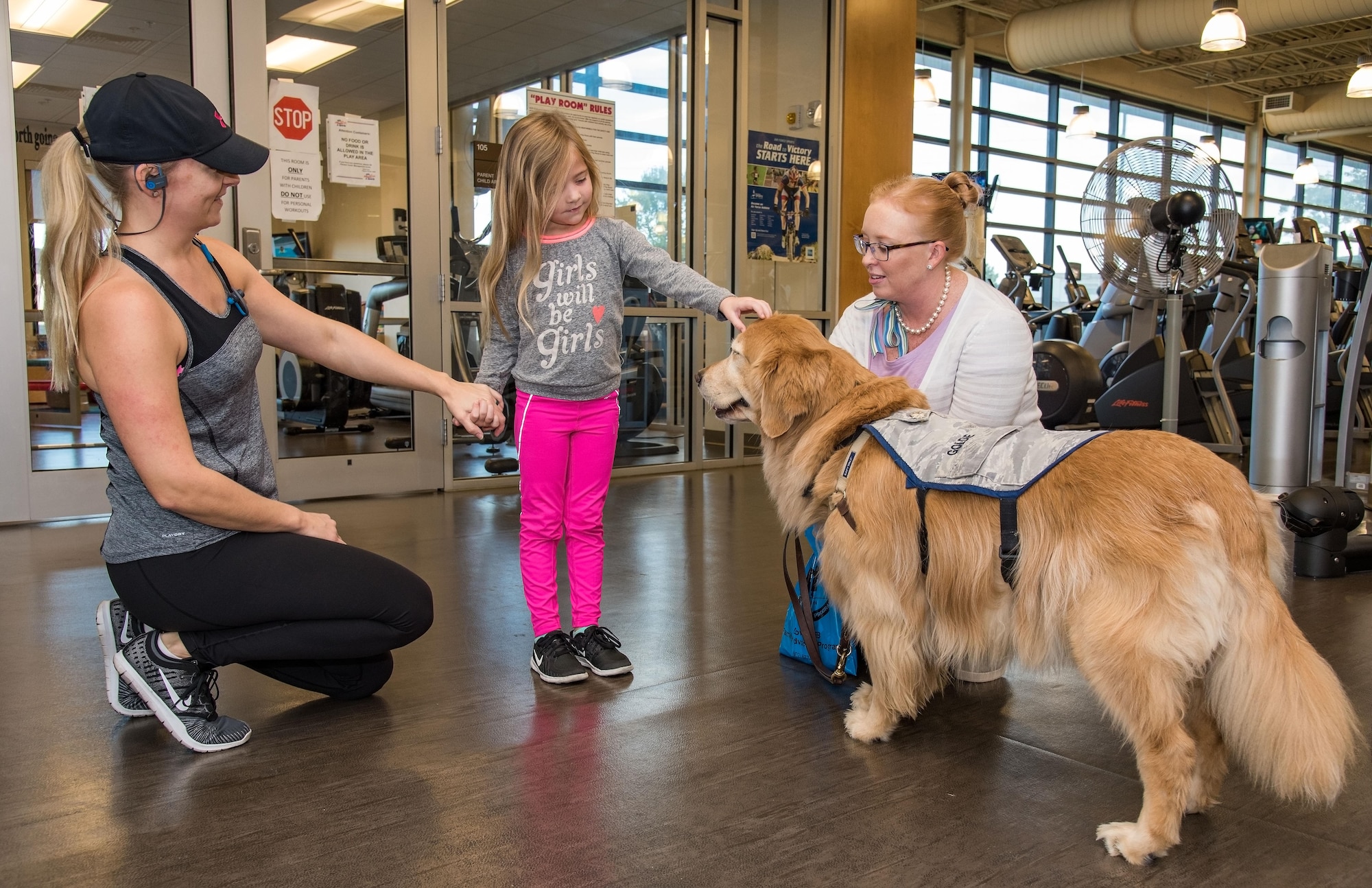 Addison Burrows, center, pets Lt. Col. Goldie, the only U.S. Air Force therapy dog visiting personnel on the base as part of Family Advocacy’s Domestic Violence Awareness Month outreach, Oct. 19, 2017, at the Fitness Center on Dover Air Force Base, Del. Addison is the daughter of MaryAnne Burrows, pictured on the left, and Master Sgt. Chris Burrows, 436th Logistics Readiness Squadron. (U.S. Air Force photo by Roland Balik)