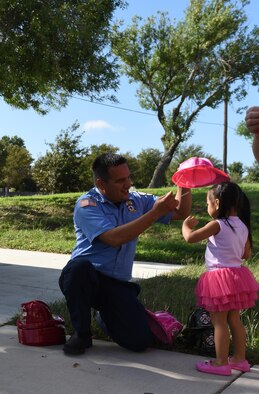 Miguel Chacon, 47th Civil Engineering Squadron lead fire fighter, gives fire hats out to children at Laughlin Air Force Base, Oct. 20, 2017. Laughlin fire dogs volunteered to read to the children at the base library to help them understand a firefighter’s job. (U.S. Air Force photo/Airman 1st Class Anne McCready)
