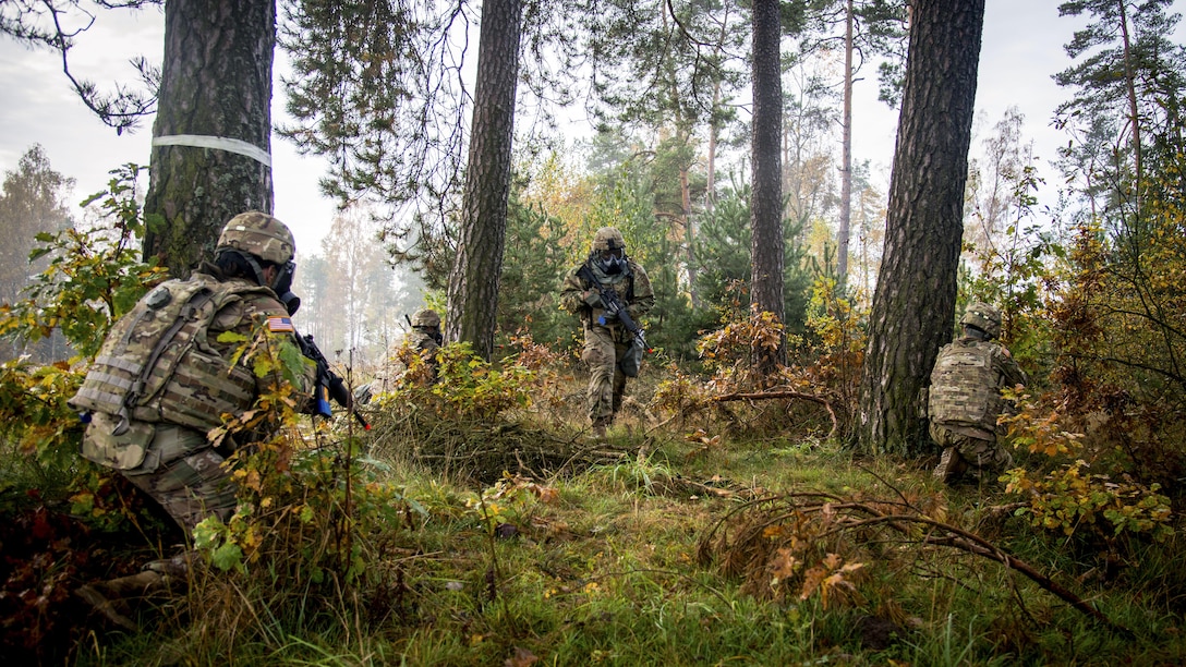 Soldiers move around trees with weapons.
