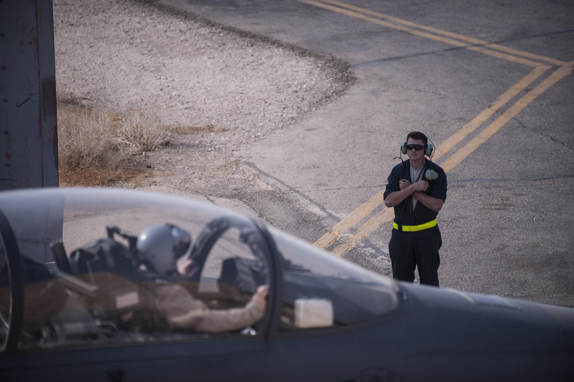 A crew chief assigned to the 332nd Expeditionary Maintenance Squadron motions for pilots to hold their position prior to takeoff October 9, 2017 in Southwest Asia. During their time in the region, maintenance Airmen set a perfect record of zero combat sorties missed.