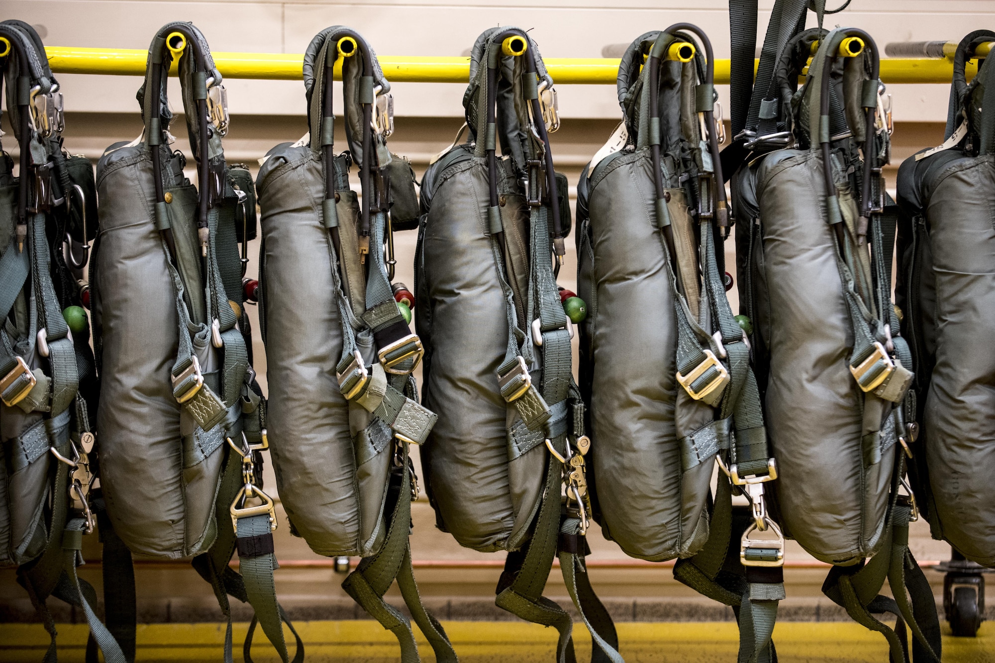 Parachute packs hang on a rack at an 86th Operations Support Squadron facility on Ramstein Air Base, Germany, Oct. 24, 2017. Aircrew Flight Equipment Airmen pack the parachutes for emergency situations. Each parachute can support more than 7,000 pounds. (U.S. Air Force photo by Senior Airman Devin Boyer)