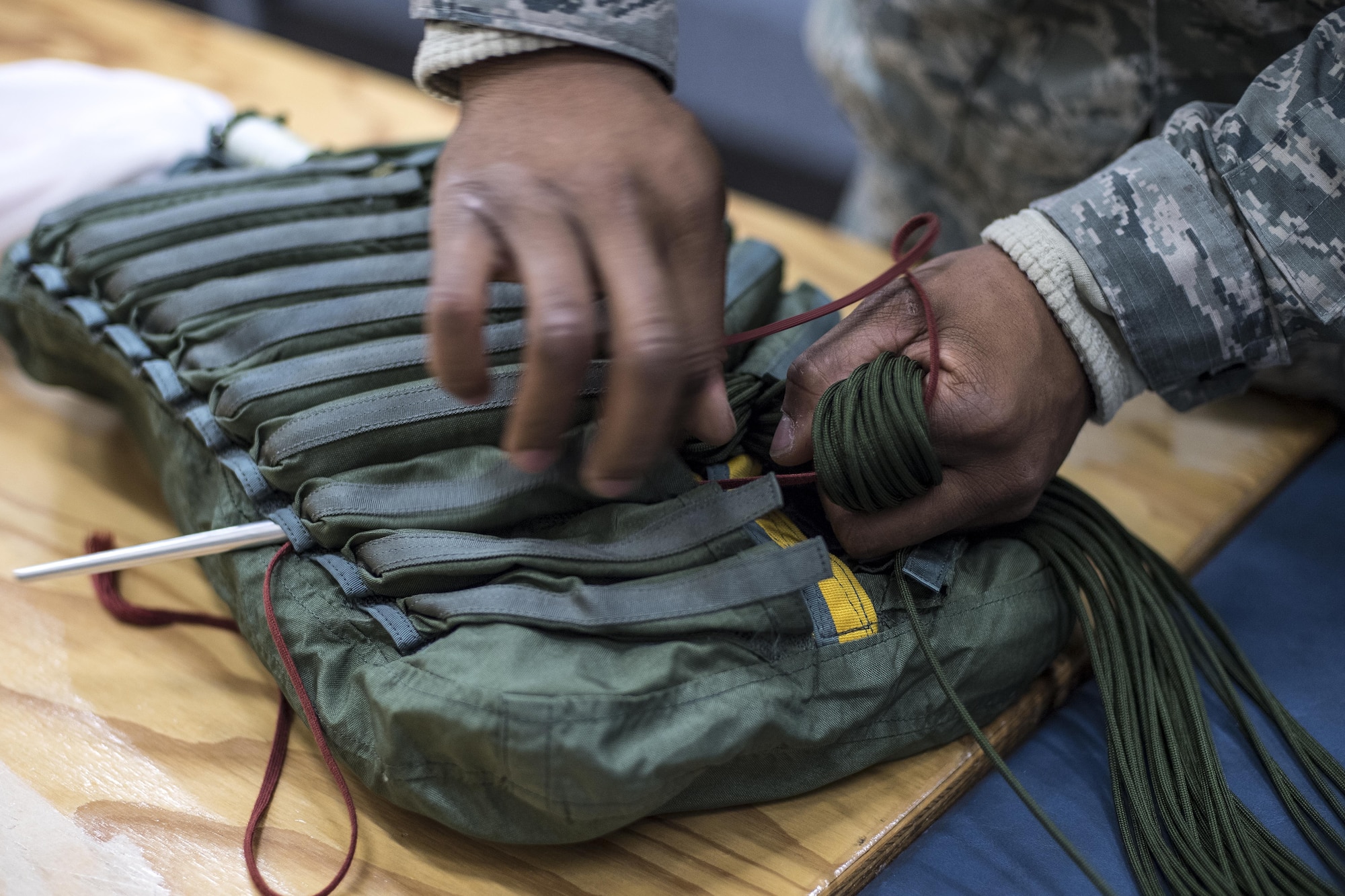 U.S. Air Force Airman 1st Class Jayson Fox, 86th Operations Support Squadron Aircrew Flight Equipment technician, packs parachute cord into a pack on Ramstein Air Base, Germany, Oct. 24, 2017. Fox uses stow tools to thread groups of the parachute cord into their designated pockets. When the parachute releases, it then pulls the cord out of the pockets within seconds. (U.S. Air Force photo by Senior Airman Devin Boyer)