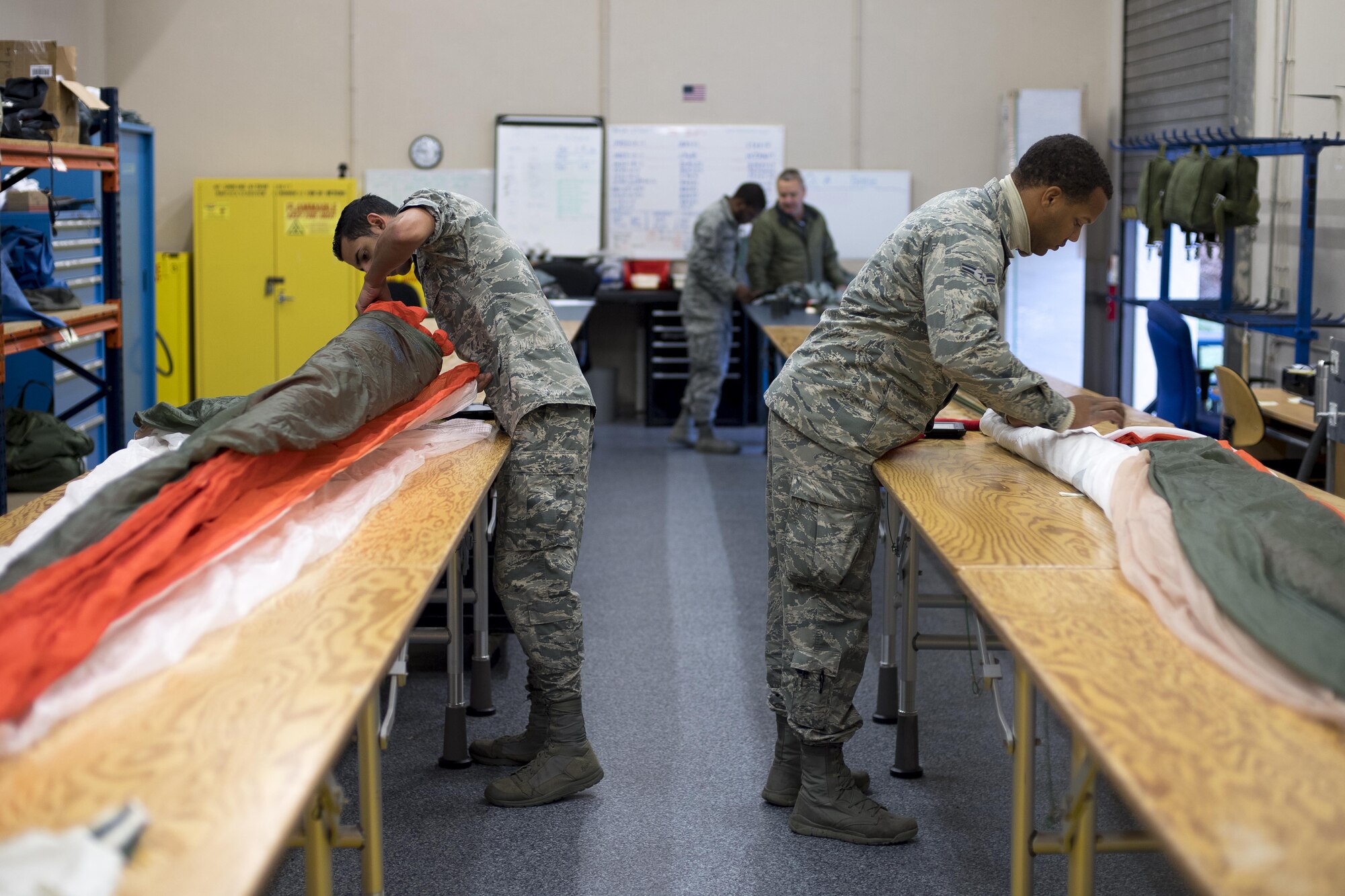 U.S. Air Force Airmen 1st Class Ricardo Nazario-Colom and Jayson Fox, 86th Operations Support Squadron Aircrew Flight Equipment technicians, prepare personnel parachutes for packing on Ramstein Air Base, Germany, Oct. 24, 2017. Aircrew Flight Equipment technicians follow a strict checklist to make sure the parachutes are operable before packing them. (U.S. Air Force photo by Senior Airman Devin Boyer)
