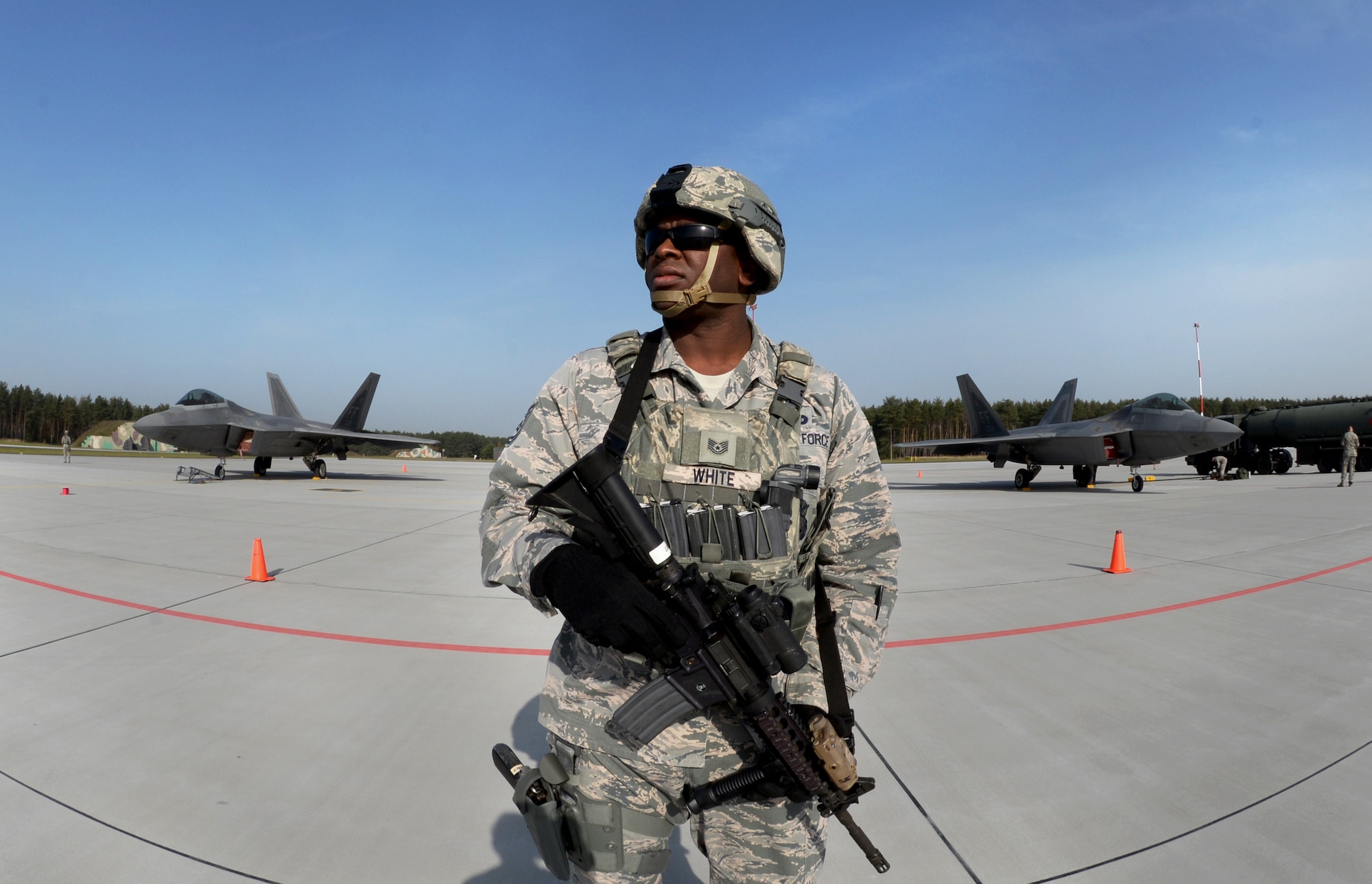 U.S. Air Force Tech. Sgt. Paul White, 633rd Security Forces Squadron flight chief, stands guard of F-22 Raptors from the 1st Fighter Wing, Joint Base Langley-Eustis, Va., Oct. 17, 2017, at Powidz Air Base, Poland. This forward deployment is an opportunity for the F-22s to train alongside U.S. and allied air force aircraft in a realistic training environment. (U.S. Air Force photo by Senior Airman Tenley Long)