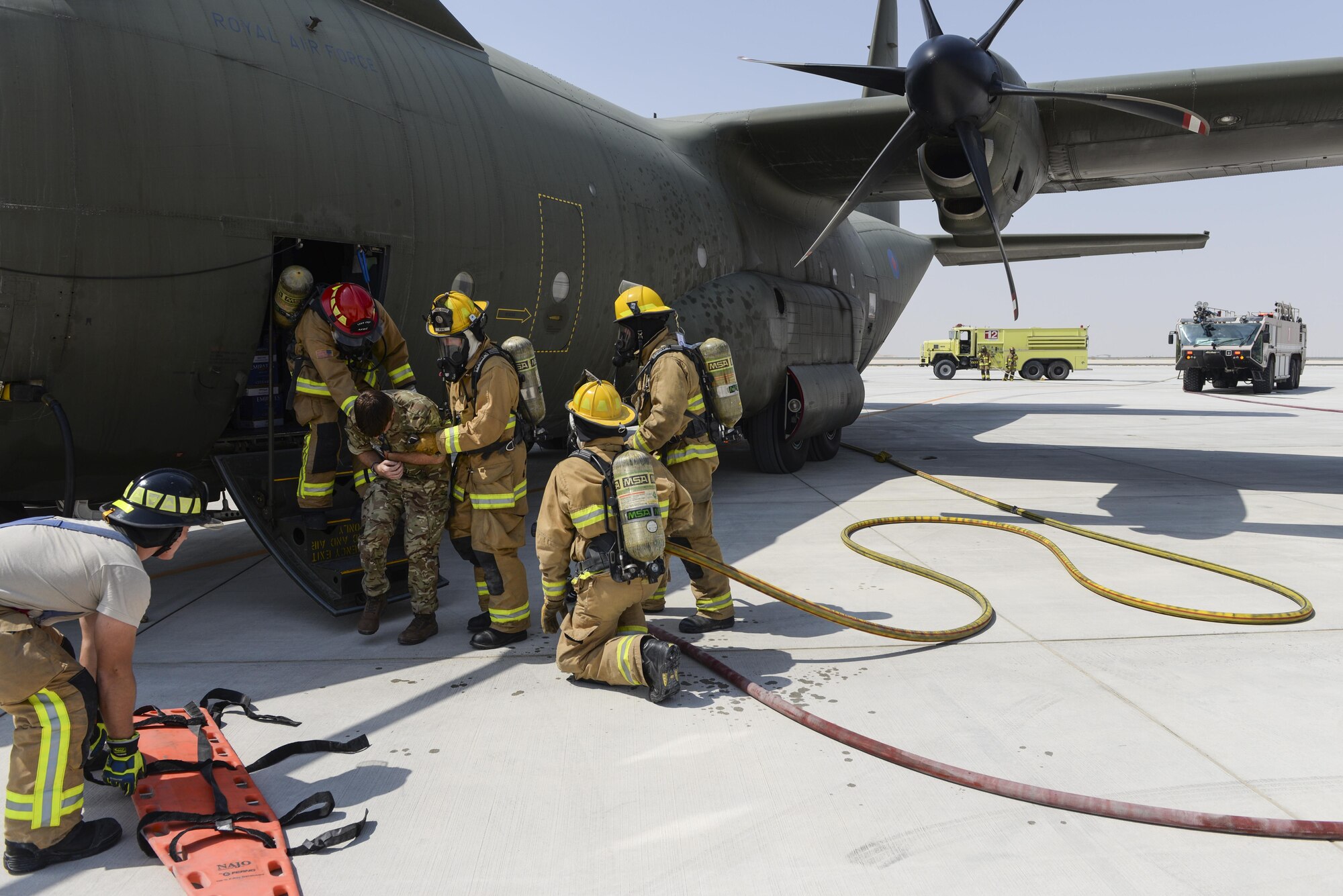 U.S. Air Force firefighters assigned to the 379th Expeditionary Civil Engineering Squadron assist a Royal Air Force member, simulating a casualty, from a C-130J Hercules at Al Udeid Air Base, Qatar, Oct. 3, 2017.