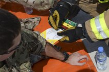 A U.S. Air Force firefighter assigned to the 379th Expeditionary Civil Engineering Squadron, notes the condition of a Royal Air Force member on his mass casualty incident tag during an accident response exercise on the runway at Al Udeid Air Base, Qatar, Oct. 3, 2017.