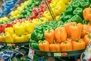 Different colored peppers sit on shelves in a grocery store.