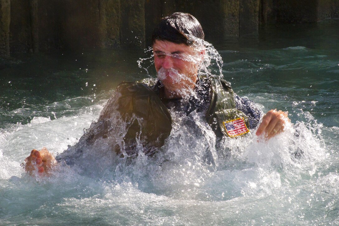 A sailor pops up from the water after jumping from a pier during training.