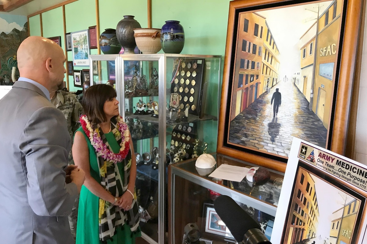 Two people look at a painting in a gallery area.