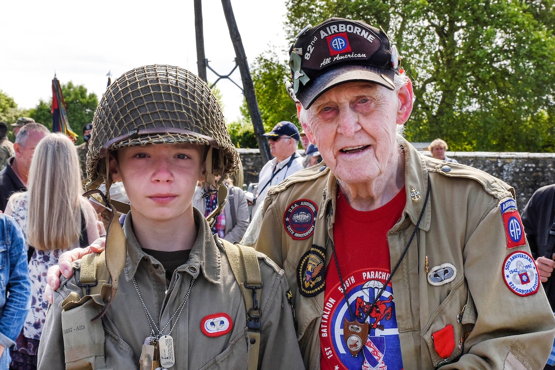 A World War II veteran poses for a picture with a young re-enactor.