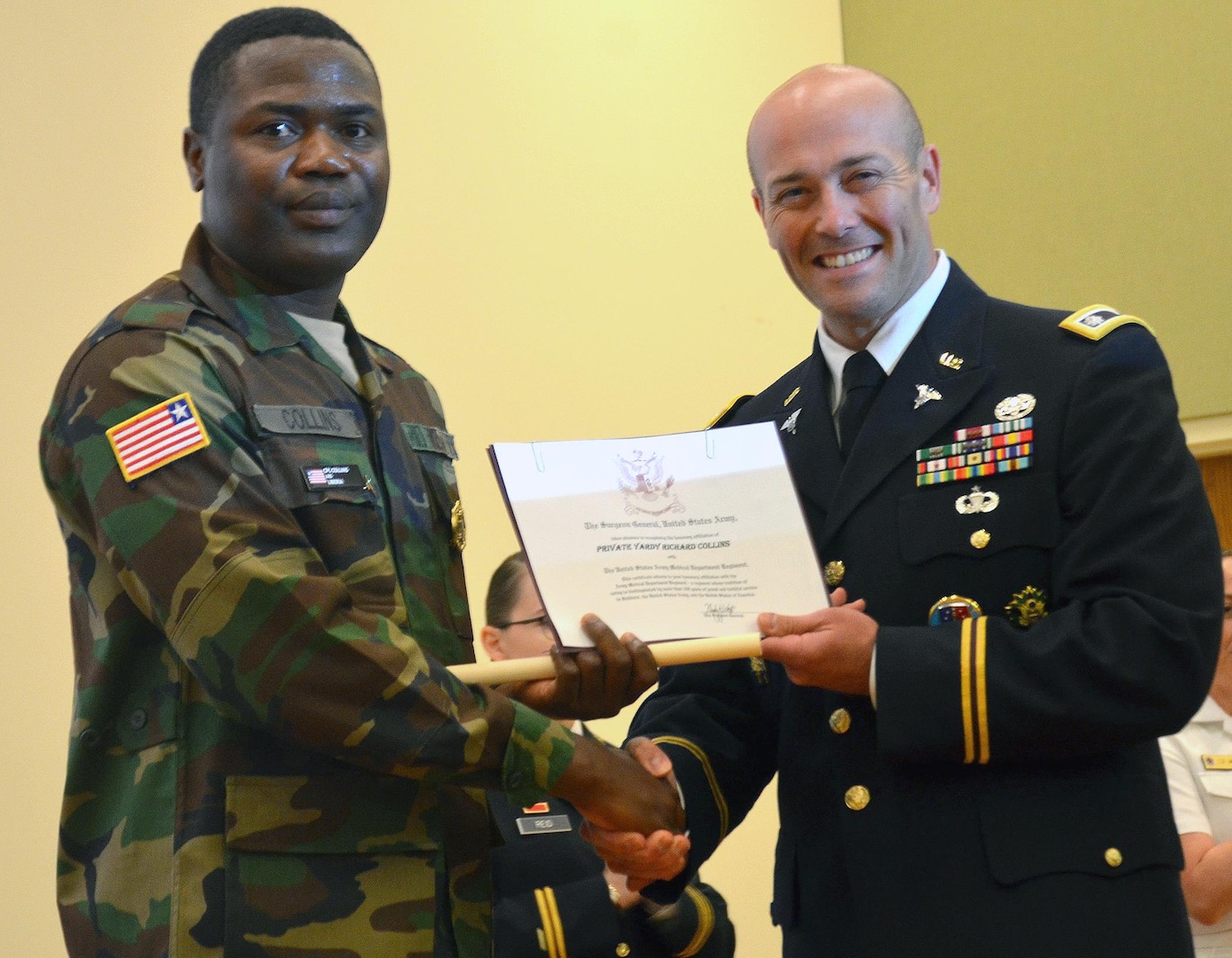 Pfc. Yardy Collins from Monrovia, Liberia, receives a certificate making him an honorary member of the Army Medical Department regiment certificate from Lt. Col. Paul Lang, Army service lead for the Medical Education and Training Campus preventive medicine specialist program, during the course graduation ceremony Oct. 20 at Joint Base San Antonio-Fort Sam Houston.  Collins is the first international military student from Liberia to graduate from the program.