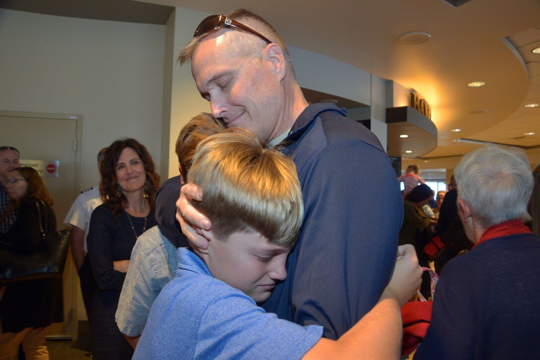 Navy captain receives a warm embrace from his sons at homecoming.