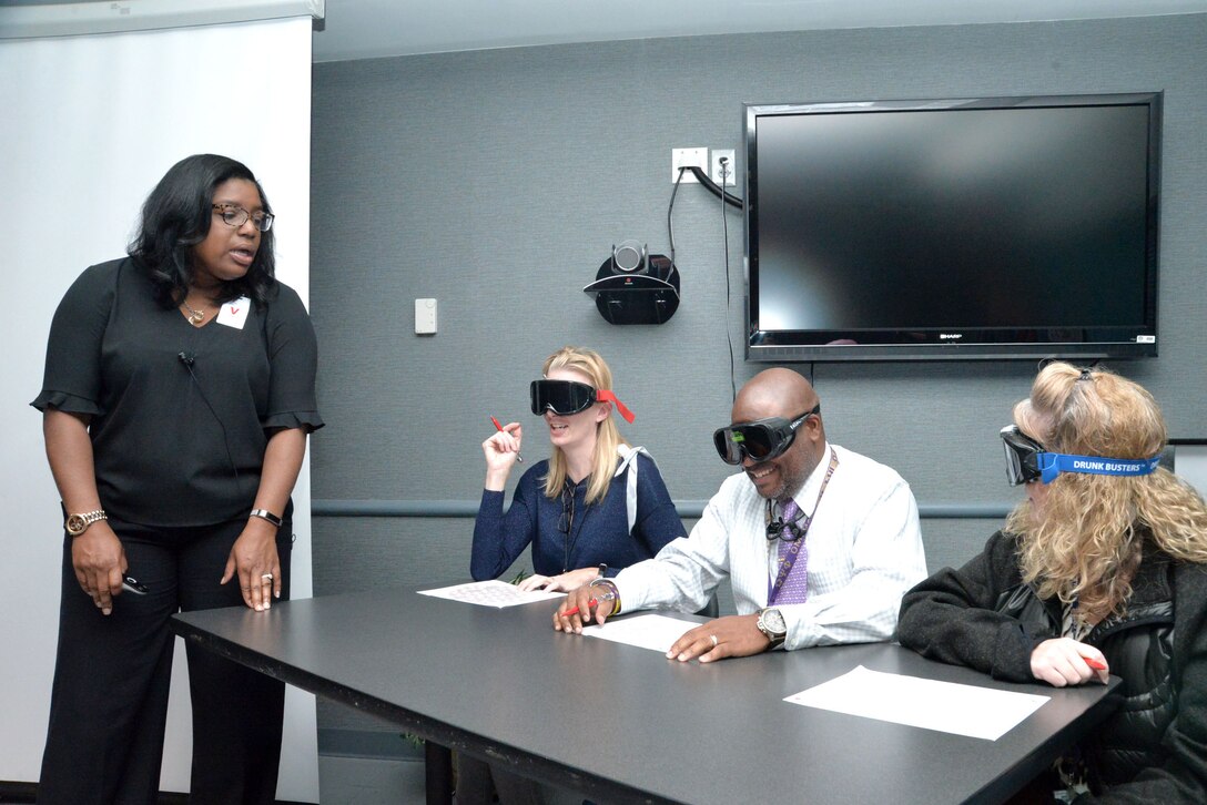 Wanda Gilbert, Employee Assistance Program coordinator with Redstone Arsenal, leads three employees of the U.S. Army Engineering and Support Center, Huntsville, through a navigation exercise Oct. 24, 2017, with goggles that simulate alcohol and/or drug intoxication. Beside Gilbert are, from left, Kristal Huinker, project management specialist with the Medical Repair and Renewal Program; Christopher Barnett, lead contract specialist with Information Technology Systems; and Shannon Robbins, international administrative assistant with Ordnance and Explosives. Gilbert’s training also included a class on suicide awareness and prevention.
