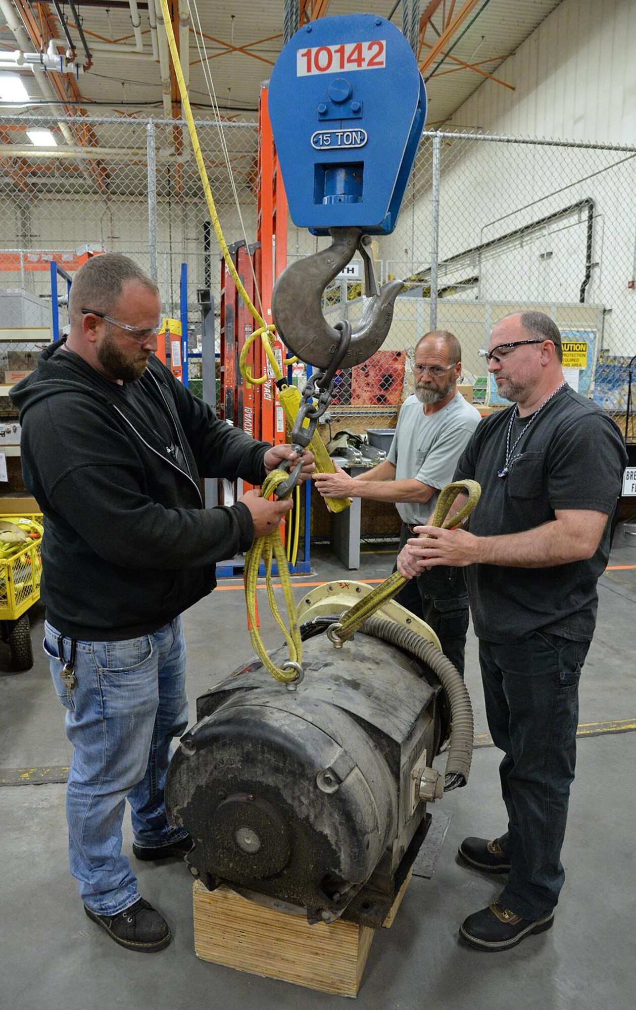 (Left to right) Brandon Ernsberger, Tyler Hatch and Robert Clements, 309th Maintenance Support Squadron lift and compressor personnel, remove a 200-horsepower electric compressor motor from a crane in building 843 on Oct. 23, 2017 at Hill Air Force Base, Utah.