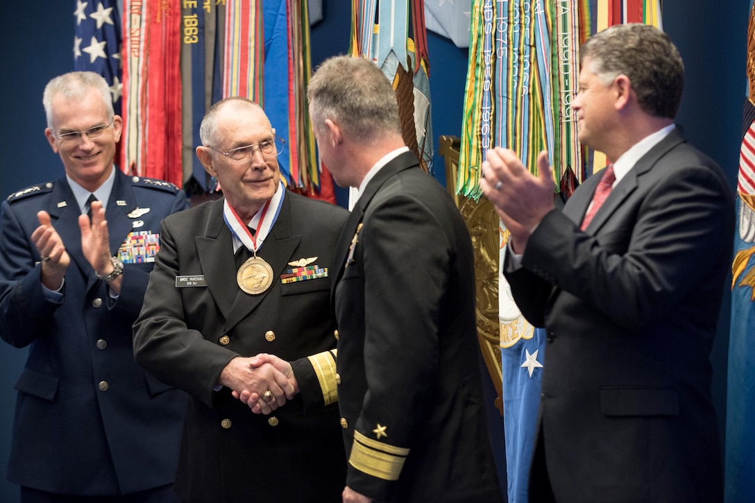The vice chairman of the Joint Chiefs of Staff claps with others on stage.