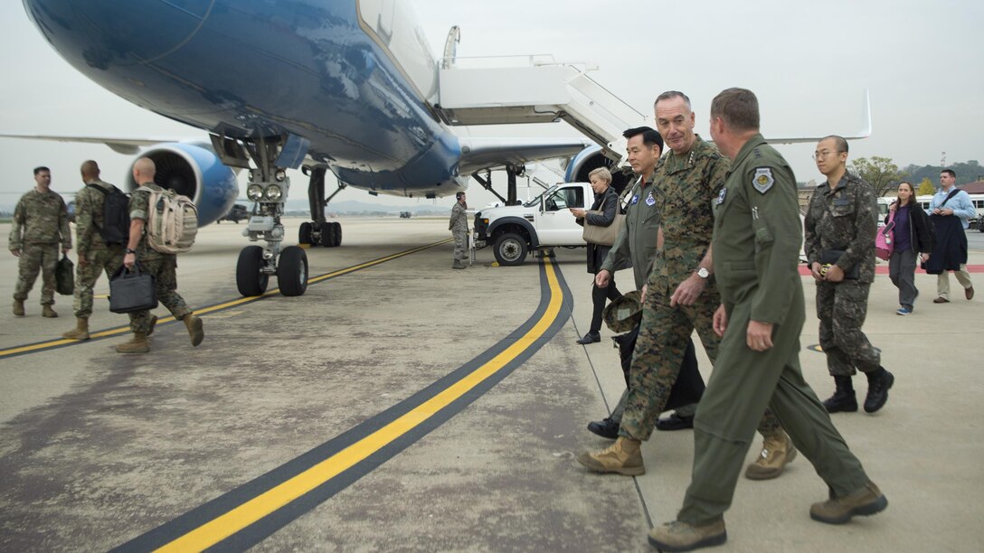 Marine Corps Gen. Joe Dunford walks and talks with others on a flightline.