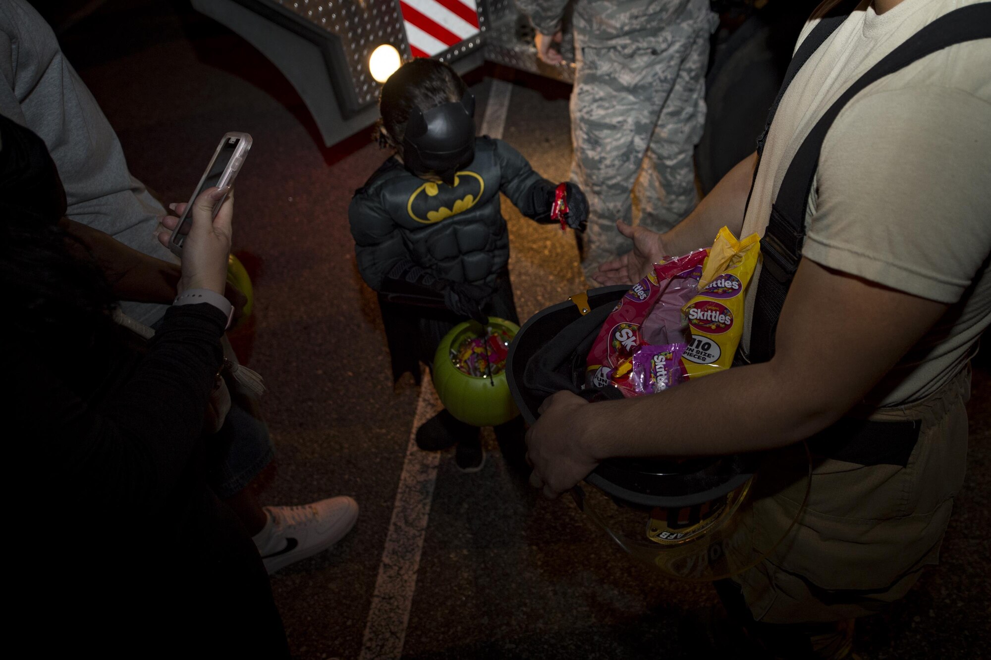 An Airman from the 23d Civil Engineer Squadron holds a helmet filled with candy at the Trunk or Treat event Oct. 20, 2017, at Moody Air Force Base, Ga. More than 3,500 Airmen and their families participated in the annual Trunk or Treat event hosted by the 23d Force Support Squadron Youth Programs. (U.S. Air Force photo by Andrea Jenkins