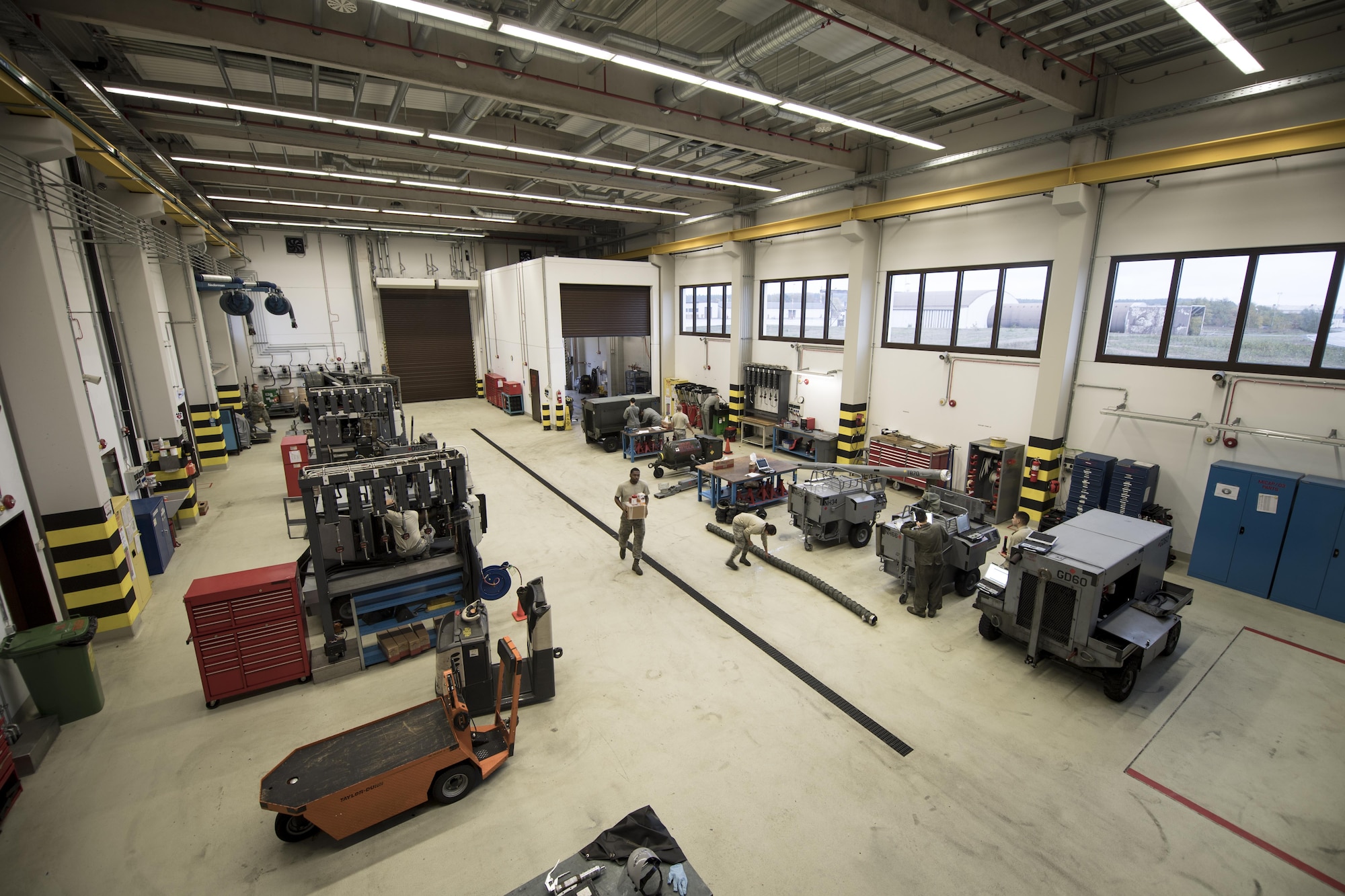 U.S. Air Force Airmen assigned to the 86th Maintenance Squadron Aerospace Ground Equipment flight perform their duties at the AGE facility on Ramstein Air Base, Germany, Oct. 25, 2017. The facility is designed for optimal efficiency. The AGE technicians can pull broken equipment straight through the bay, work on them, and send them back out to the flightline without obstructing work flow. (U.S. Air Force photo by Senior Airman Devin Boyer)