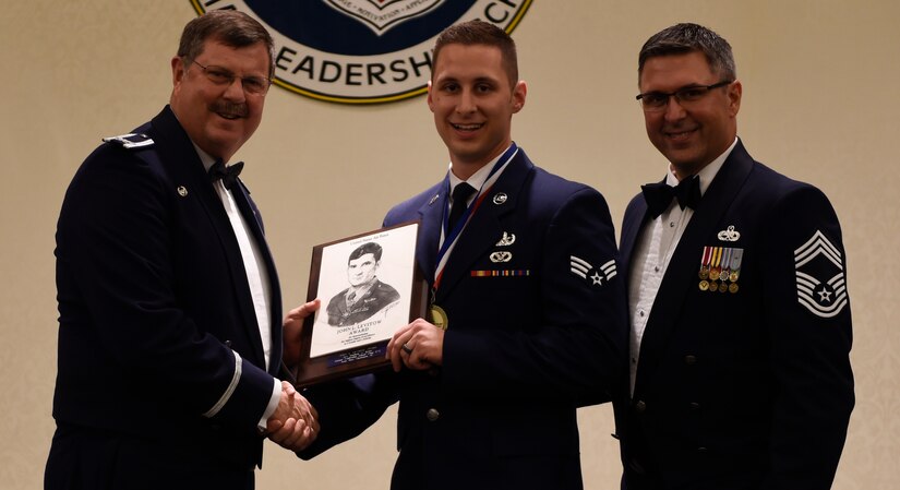 Col. Gregory Gilmore, left, 315th Airlift Wing commander and Chief Master Sgt. Jeffrey Payne, right, 315th Aircraft Maintenance Squadron superintendent, congratulate Senior Airman Matthew Koser, middle, 315th Civil Engineer Squadron member, for earning the John L. Levitow Award during the class 17-G Airman Leadership School Graduation at the Charleston Club here Oct. 25, 2017.