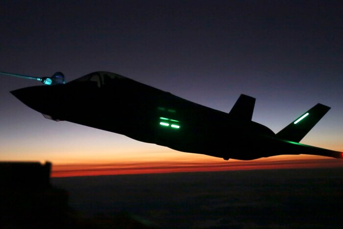 An aircraft flies at sunset.